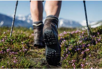 A hiker walking on a nature trail with trekking poles.