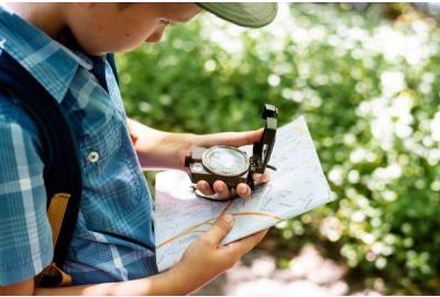 Scout reading a map with a compass in the woods