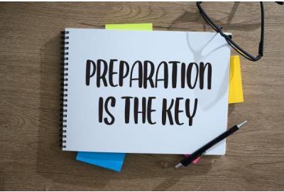 Notebook that says 'preparation is key' on wooden desk