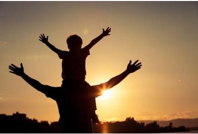 a father holding a child on his shoulders with his arms extended.