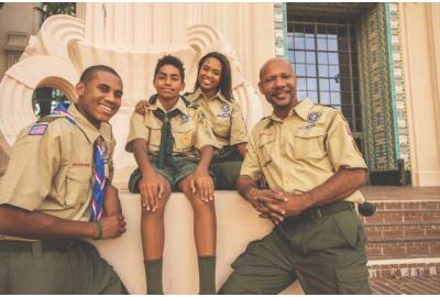 Scouts BSA short-sleeve uniform shirt and green pants on orange background.