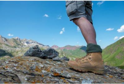 man in hiking boots on a mountain cliff on a sunny day.
