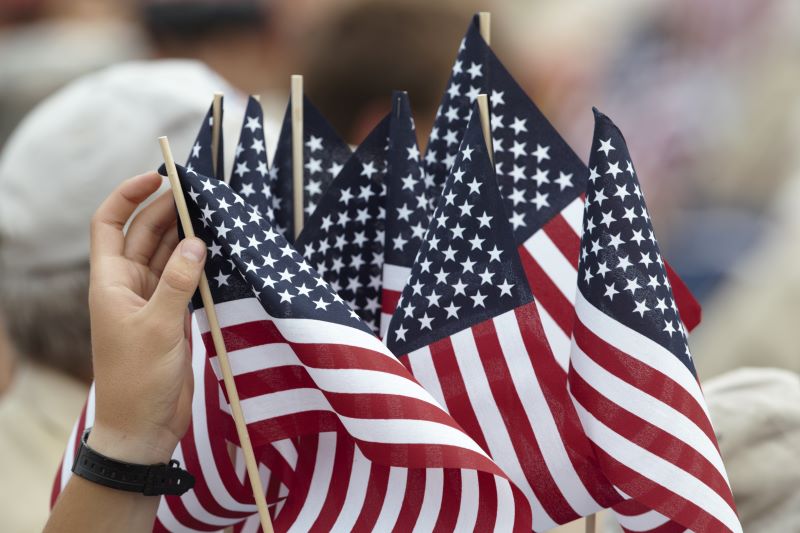 Scout holds American flags at a patriotic gathering.