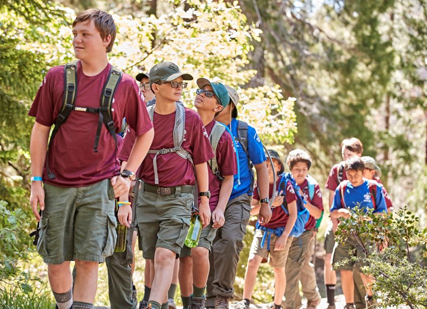 Scouts Hiking and Team-Building Adventure | Outdoor Skills and Exploration. Group of Scouts hiking on a forest trail, wearing backpacks and enjoying a team-building adventure in nature.