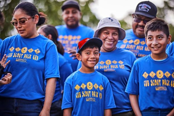 A group of Cub Scouts and their leaders from Pack 489 wearing blue uniforms smile together outdoors, highlighting the fun and camaraderie of Scouting activities.