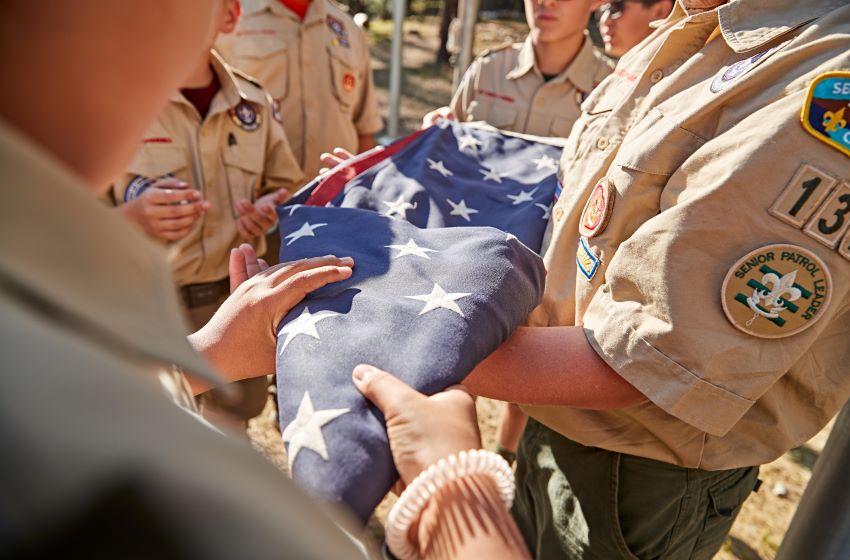 Scouts Folding the American Flag with Care Scouts in uniform folding the American flag together, showcasing respect and Scouting values during a ceremonial activity.