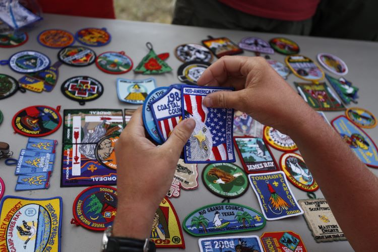 Hands of a Scout comparing different Scouting America patches at the 2017 National Scout Jamboree