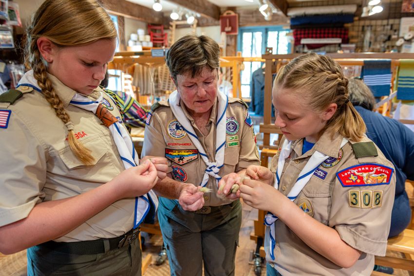 An older woman helps two young Scouts