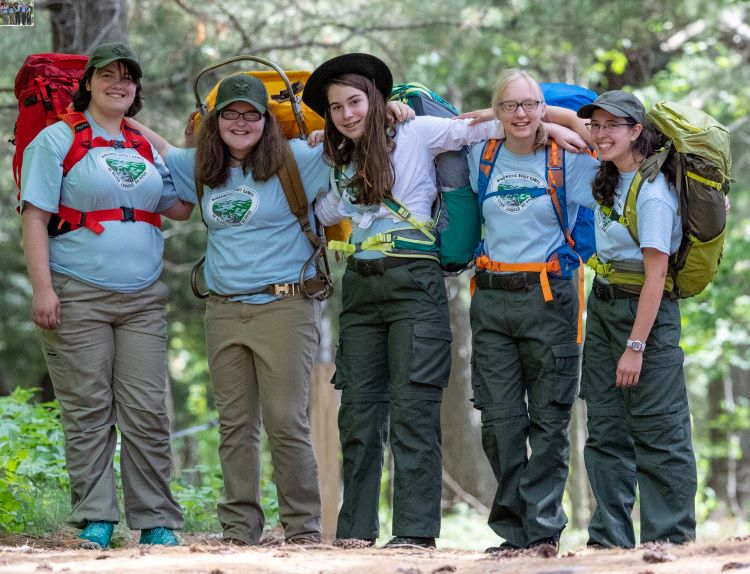 Girl Scouts pose for a picture while backpacking in a forest