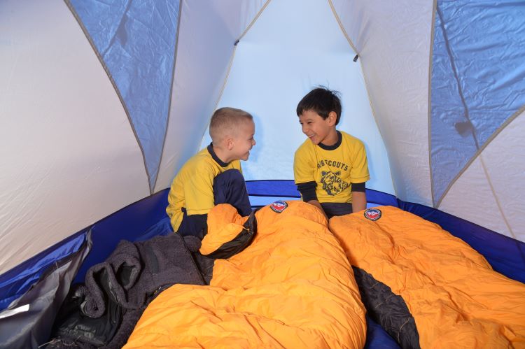 Cub Scouts in a tent fixing their sleeping bags