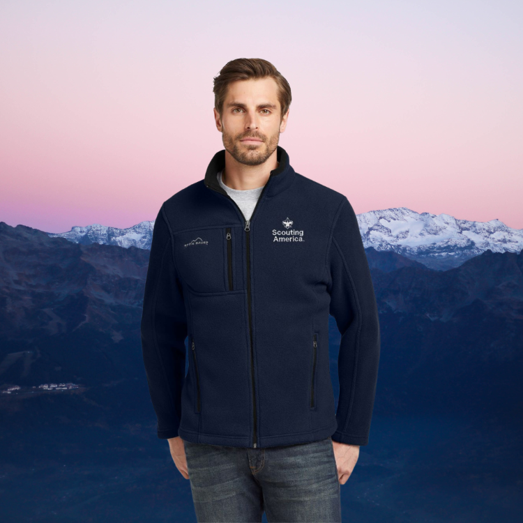 Scouting America Eddie Bauer Full Zip Fleece Jacket - Men's S-4XL A man wearing a navy blue Scouting America Eddie Bauer Full Zip Fleece Jacket, standing against a mountain landscape at dusk.