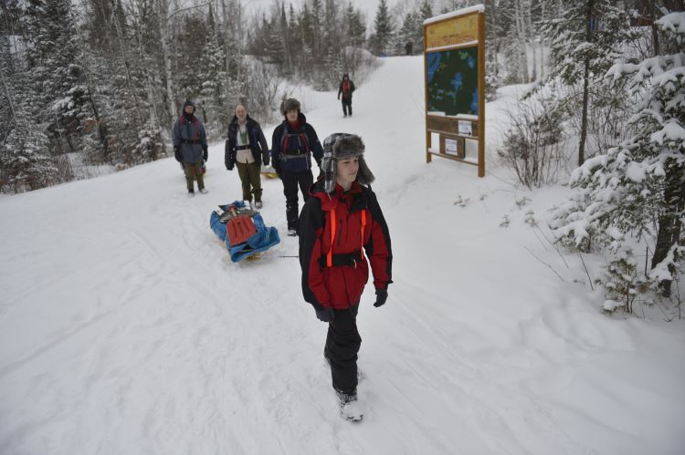 Scout carrying a backpack up a snowy mountain