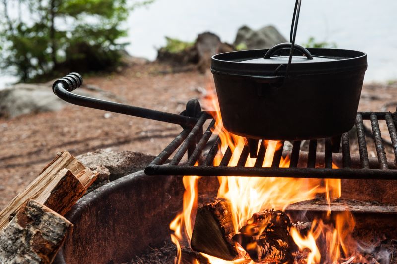 Black Dutch oven on a wire rack above a campfire