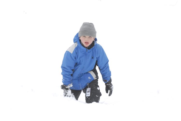 Scout in blue puffer jacket climbing up a snowy hill